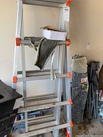 Aluminum ladder in stepladder configuration with a glove and box on a step