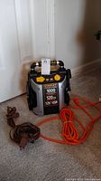 Front view of Stanley Portable Power air compressor with extension cords on carpet floor in front of door.