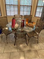 Photo of square glass top table with metal base and four faux wicker chairs in a kitchen area.