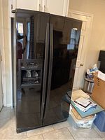 Front view of black side-by-side refrigerator showing both doors and ice/water dispenser on left door