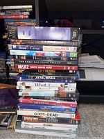 Stack of DVDs and a few visible game cases including The Bible, The Hunger Games, Hidden Secrets, Home and others.