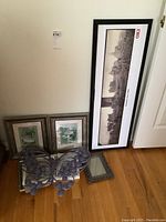 Framed art prints displayed on floor against wall including Baltimore Fire 1904 print, smaller framed prints, small frame and purple butterfly decor