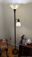 Full view of the floor lamp showing the large stained glass shade on top and smaller stained glass shade on side arm.
