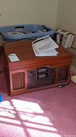 Wooden cabinet multi-function audio player with manual and remote on top.