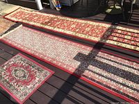 Photo showing all three rugs laid out on deck: two long runners and one small throw rug.