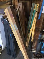 Photo showing several folded saw horses: yellow plastic adjustable ones with metal parts, and wooden ones with metal components, stacked vertically.