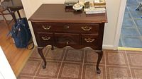 Front view of wooden Thomasville lowboy cabinet with two drawers and brass handles, showing overall shape and condition.