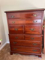 Front view of 8-drawer wood dresser with brass-tone handles and glass top