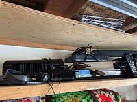 Photo showing a black tower speaker, Astron audio amplifier, various cables, and electronic devices on a wooden shelf.