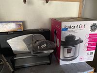 Photo showing Instant Pot box and electric food slicer with attachments on table.