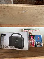 Photo showing GPX portable AM/FM shortwave radio in box with other kitchen/electronics items around