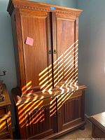 Front view of closed reproduction Craftsman style secretary desk showing paneled double doors and carved trim.