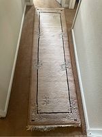 Photo showing full length of small wool runner rug placed in hallway, highlighting floral design and fringe.