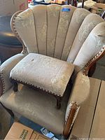 Front angled view of the velvet upholstered chair showing the floral embossed pattern, scalloped backrest, wooden carved frame details, and padded arms.