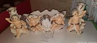 Photo showing all three cherub figural pieces: two candle holders and one decorative dish with cherubs.