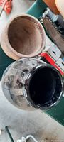 Top view of early unglazed clay pot and black glazed stoneware crock showing interior and exterior details.
