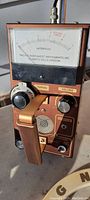 Close-up of the metal detector's control box showing the analog intensity meter, tuning and volume knobs, and a handheld grip.