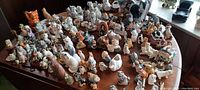 Wide view of a large assortment of vintage ceramic cat figurines laid out on a table showing various types, sizes and styles.