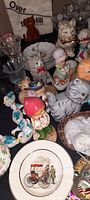 Photo showing multiple ceramic animal figurines mostly cats, including a red hat cat, gray cat with bow tie, and other small figurines.