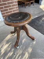 Side view showing wooden legs and casters of antique desk chair.