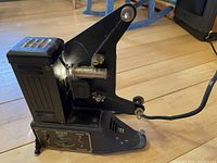 Side view of the antique Univex 8mm film projector showing the main body, film path, and power cord.