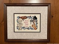 Framed cross stitch artwork showing the full piece with matte and frame, decorative musical theme with text.