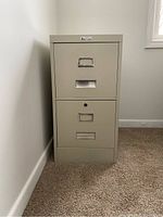 Full front view of the beige metal filing cabinet with two drawers and locking mechanism on bottom drawer.