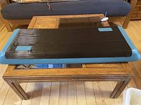Black and blue Reebok step platform on a wooden table, showing surface and edges