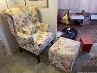 Floral patterned wingback sofa chair and matching ottoman displaying fabric pattern and overall condition