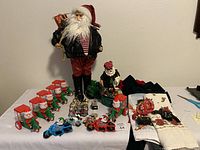 Wide view of the full lot displayed on a table including a full-size biker Santa figure, multiple Santa motorbike candy dispensers, motorcycle miniatures, holiday towels, bows, and green garland.