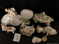 Photo showing the full collection of assorted figurines including cherubs, animal figures, and decorative dishes with chips visible on some items