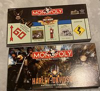Two Harley-Davidson Monopoly board game boxes: top is the sealed Live to Ride Edition showing game board design with Harley-Davidson themed property spaces; bottom is the opened Authorized Edition box with Harley-Davidson riders on cover.