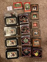 All 16 Harley-Davidson ornaments arranged on carpet showing variety of boxes and packaging including Cavanagh and Hallmark Keepsake.