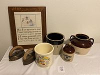 Full view of all items showing irons, framed sampler, crocks, and jug.