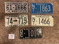 Front view of all five Kansas license plates from years 1949, 1950, 1963, 1967, and 1969 arranged on carpet showing condition and text.