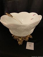 Milk glass punch bowl on ornate metal stand with plastic ladle inside, showing cracks on bowl and wear on metal finish