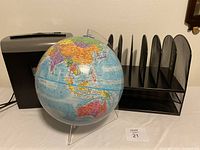 Photo showing paper shredder, globe, and wire mesh file organizer placed side by side on surface