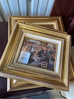 Set of three ornately framed prints stacked, showing gold-toned frames and visible wear.