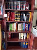 Full view of a dark wooden bookshelf containing various books, mostly legal and reference titles, arranged on five shelves.