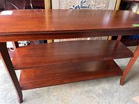 Front view of rectangular wooden console table showing top surface and two lower shelves.