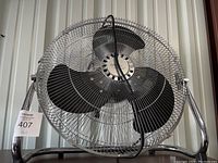 Front view of a metal oscillating floor fan with three black blades and a wire cage protecting the blades.