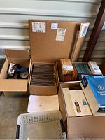 Overview of multiple office supply boxes and packages including cardboard file folders, plastic trays, and hanging folders.