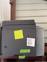 Side view of a gray Canon printer with a label showing measurements and lot number 413