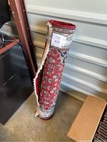 Photo of the rolled rug showing detailed red and white pattern with floral designs.