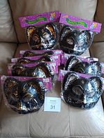 10 kitty cat face masks in black with gold and silver painted decorative details, all packaged individually.