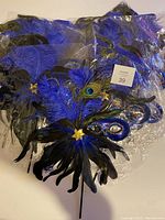 Set of 12 blue and black feathered masquerade masks in plastic packaging, showing multiple masks stacked