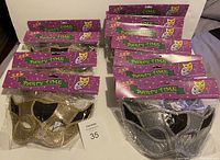 Overview of 10 party masks in original packaging; mostly silver with some gold masks
