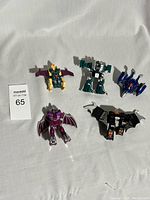 Five robotic animal Transformer toys arranged on a white fabric surface showing variety of colors and forms.