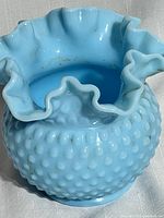 Close-up of blue hobnail milk glass vase showing ruffled top and hobnail texture