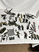 Overview of Lanard GI Joe action figures, helicopters, motorcycles, and various weapons and accessories arranged on a white surface.